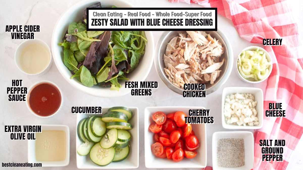 Top-down view of ingredients for a zesty salad with blue cheese dressing, including fresh greens, cooked chicken, cucumber, cherry tomatoes, celery, blue cheese, and various condiments.