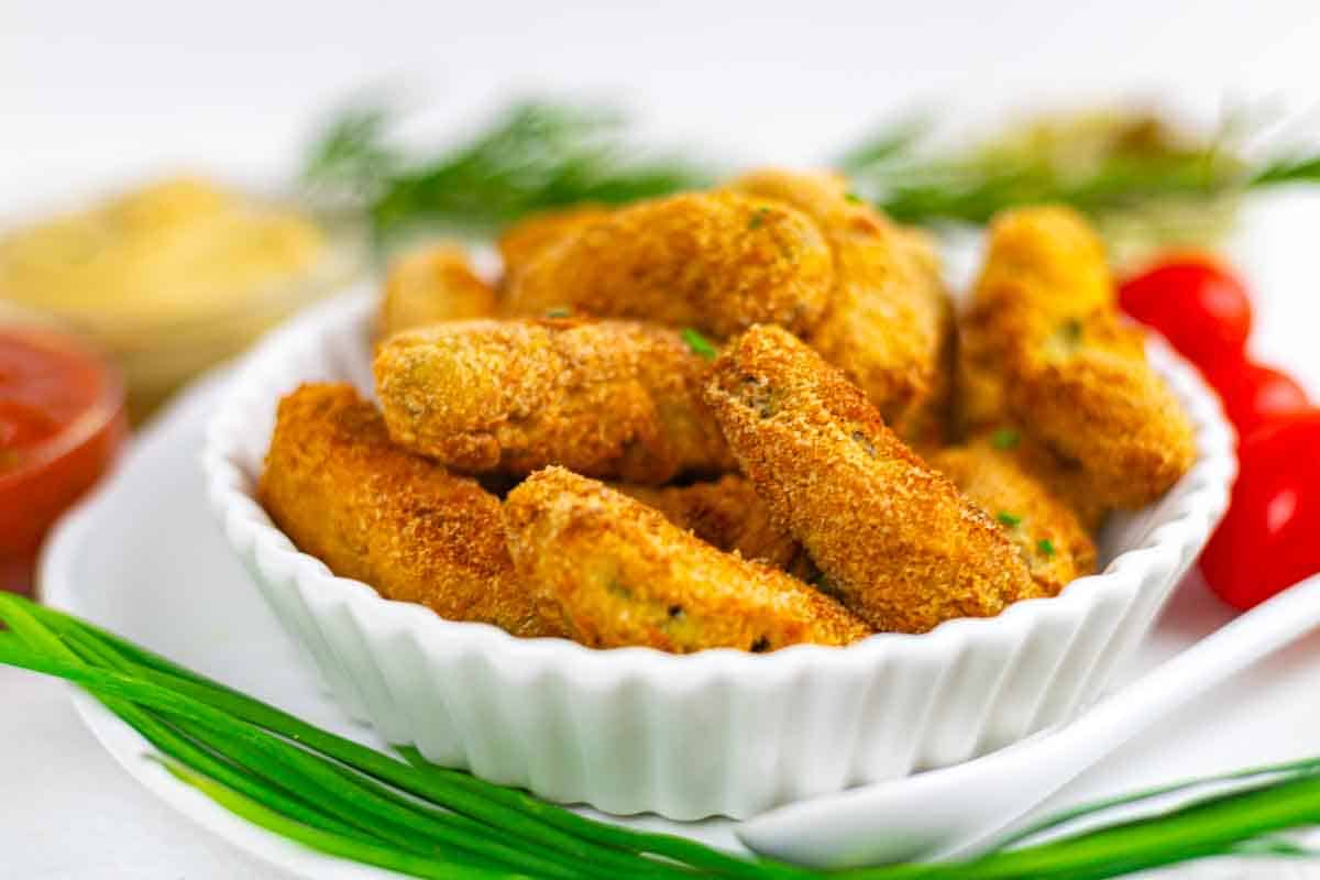 Golden baked pickles with fresh herbs garnish.