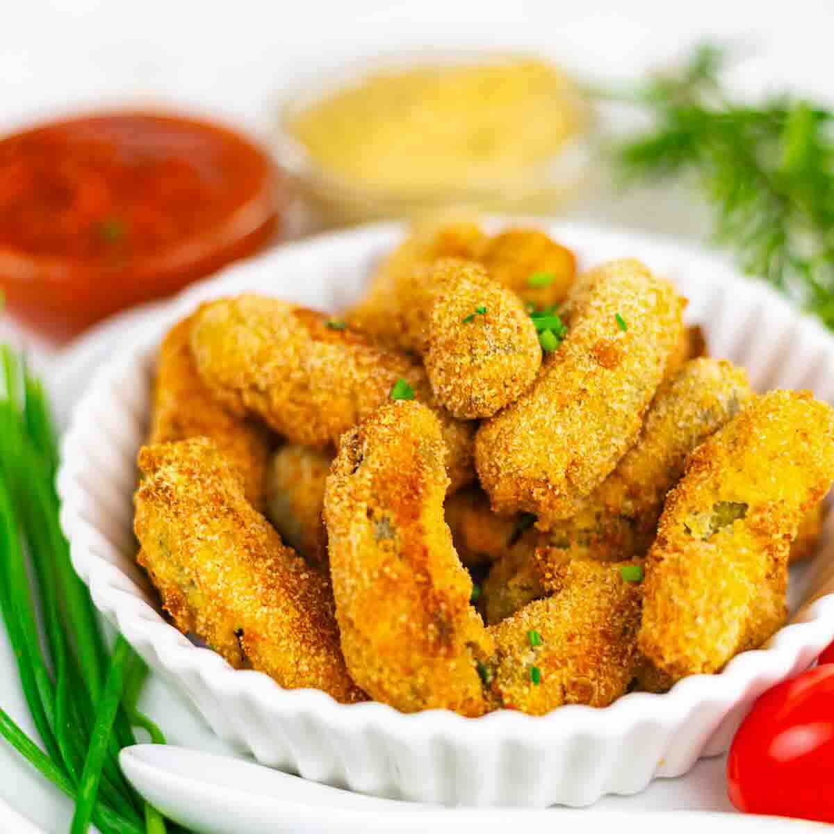 Crispy baked pickles in white serving bowl.