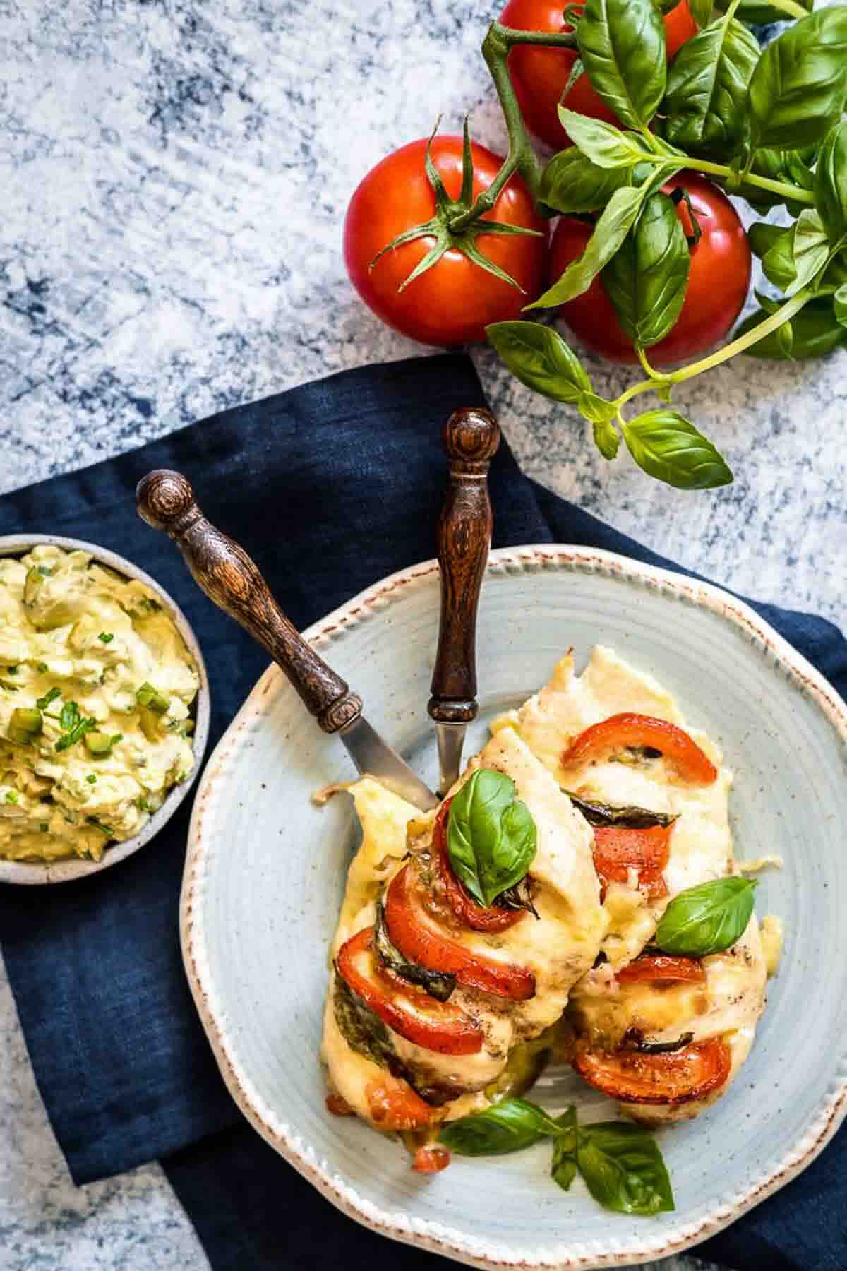 Plate of stuffed chicken with tomatoes and basil.