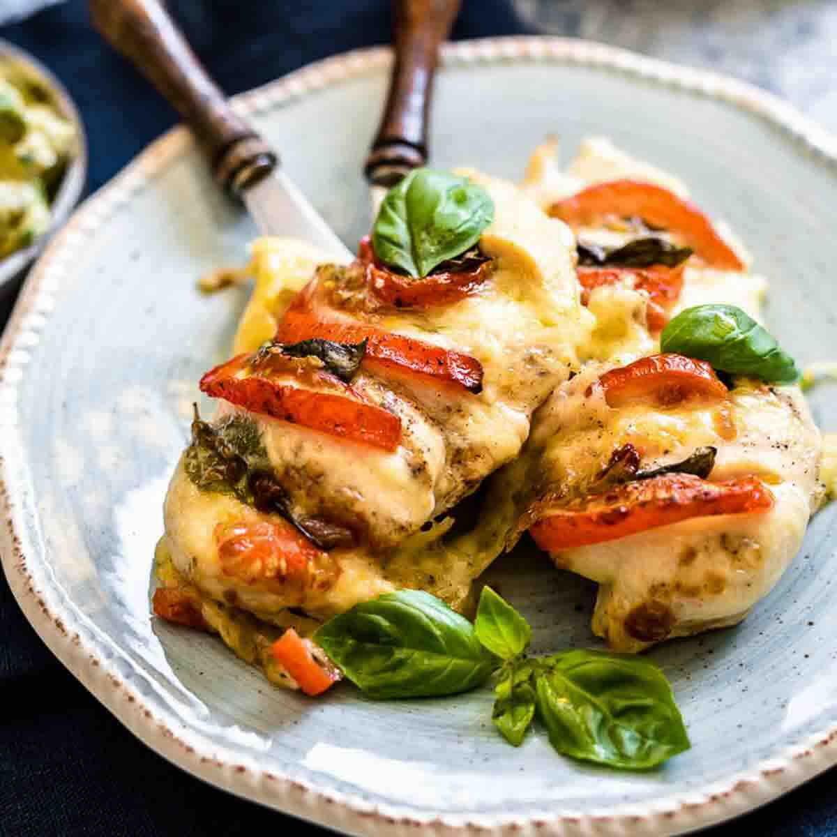 Melted cheese chicken with basil garnish plate.