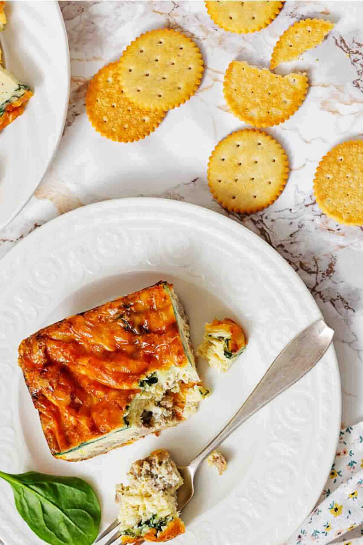 Breakfast strata slice served with crackers nearby.
