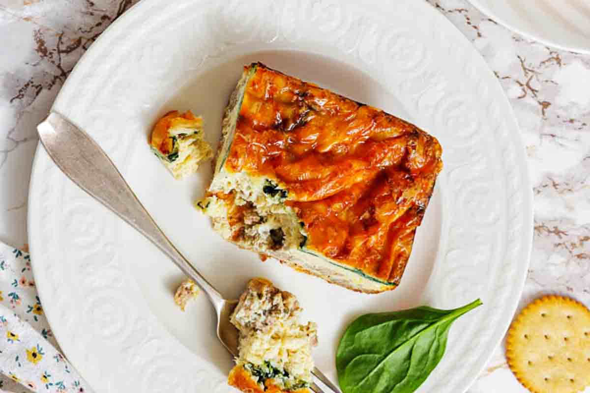 Sausage egg strata slice on white plate.