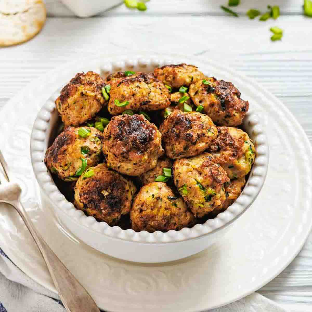 Bowl of chicken fritters with fork beside.