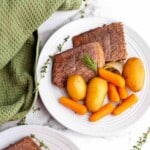 Sliced roast beef served with carrots and herbs.