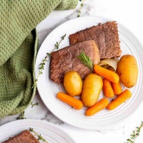 Sliced roast beef served with carrots and herbs.