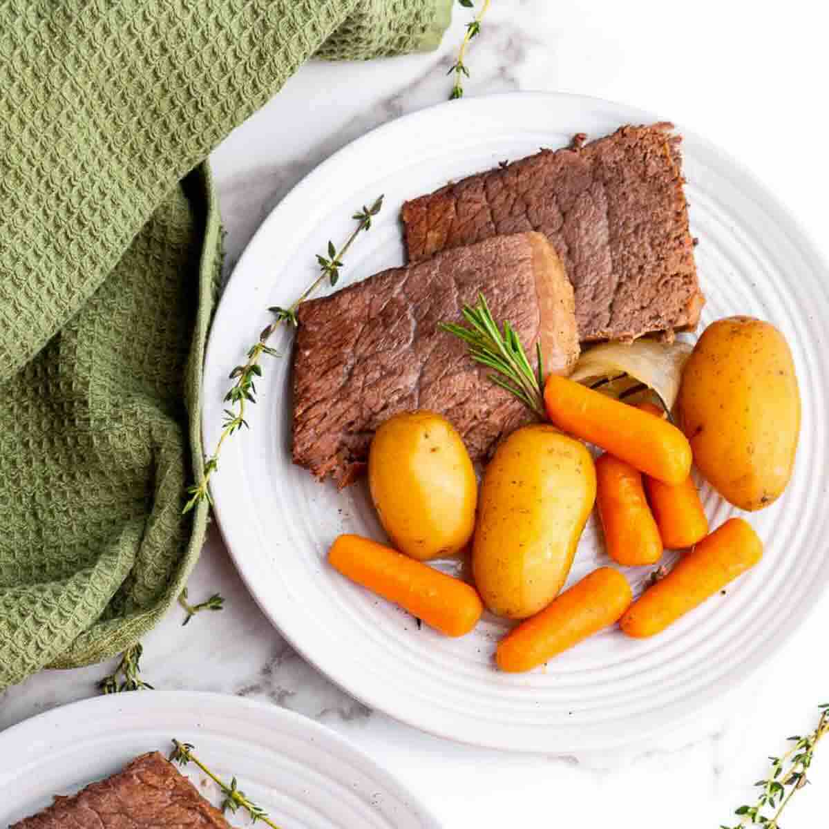 Sliced roast beef served with carrots and herbs.