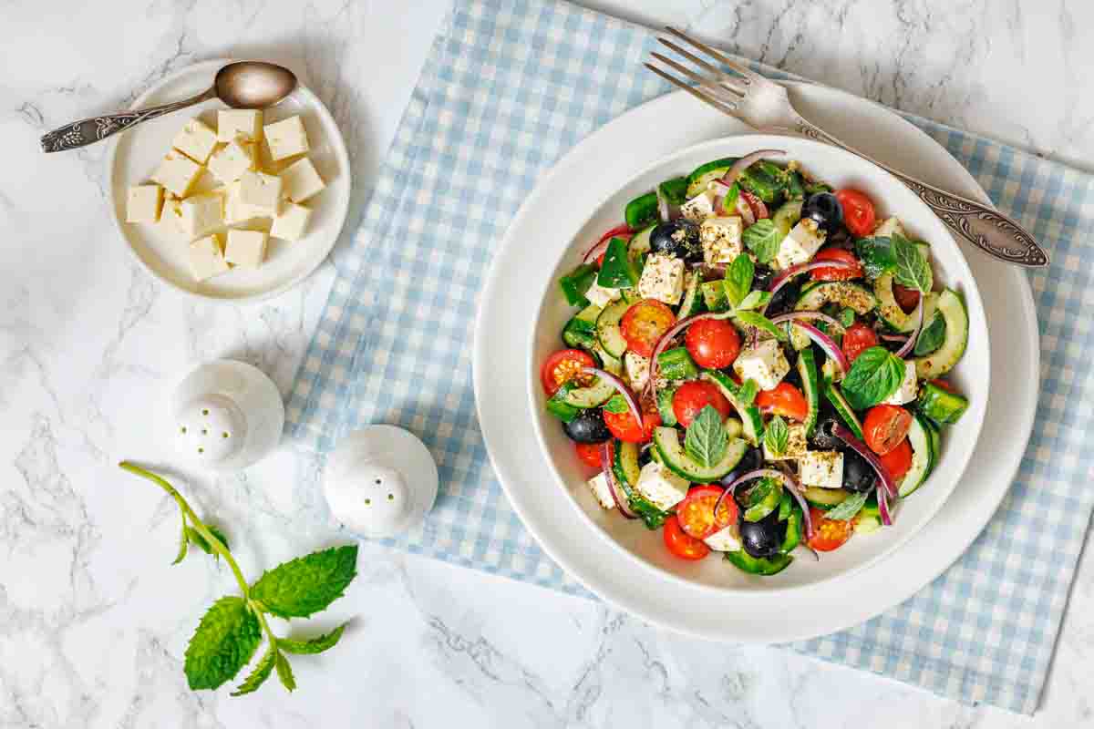 Fresh cucumber tomato feta salad on table.