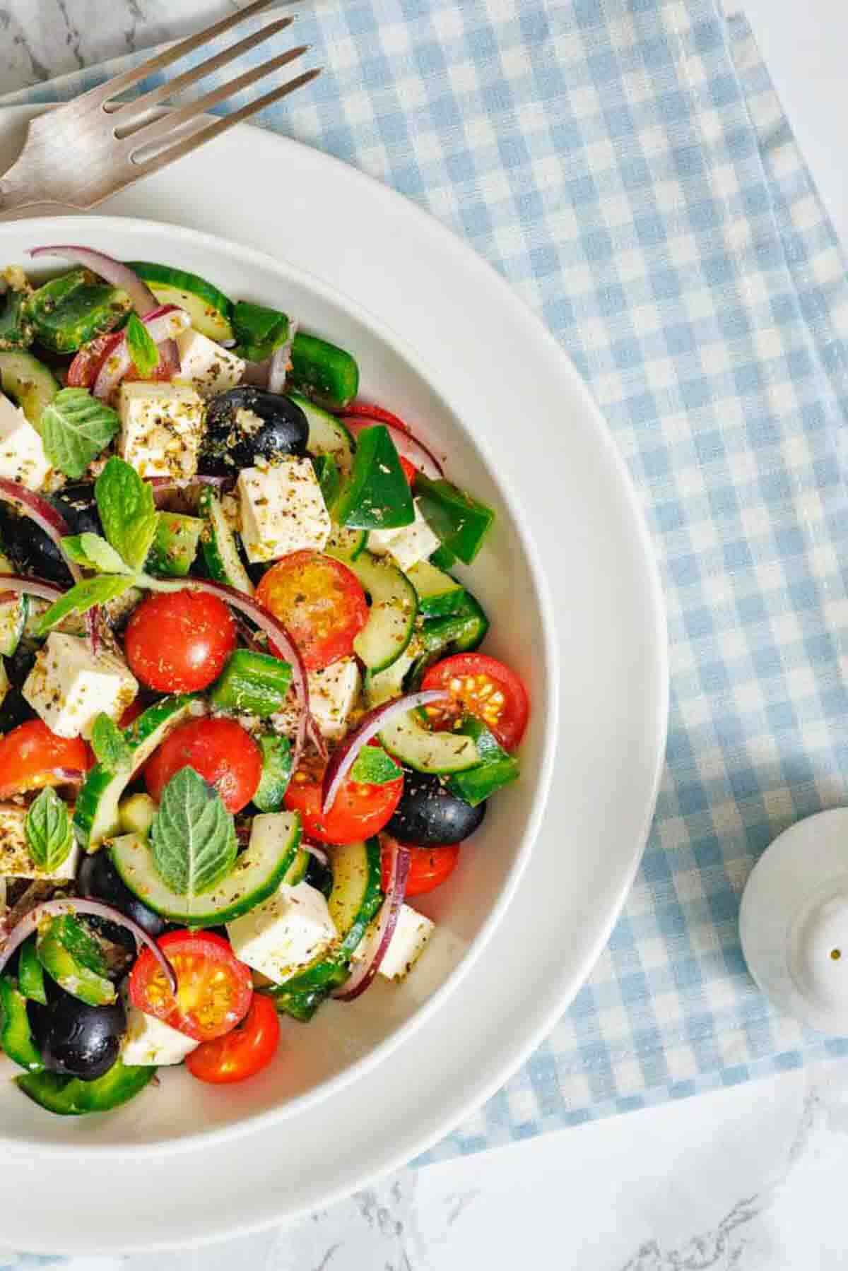 Healthy cucumber tomato salad topped with fresh herbs.