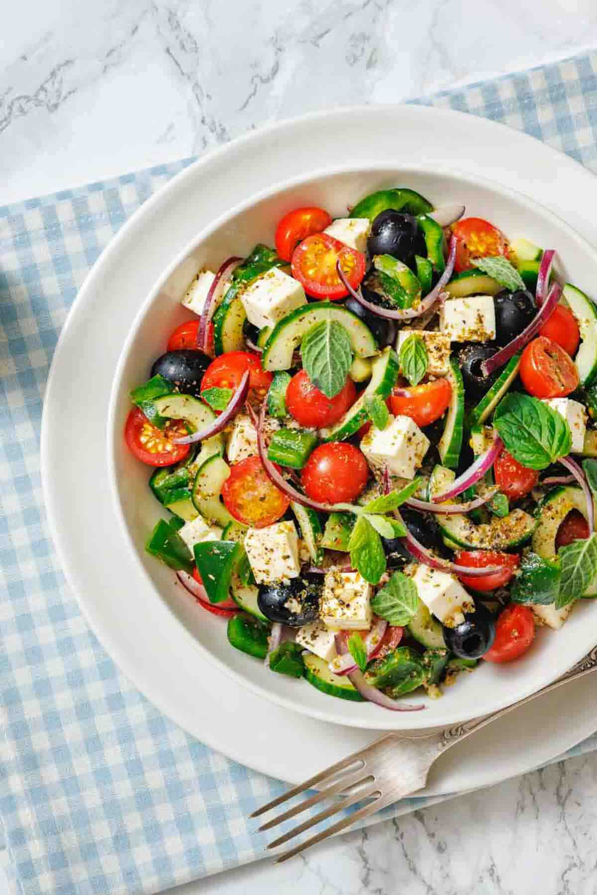 Mediterranean cucumber tomato feta salad in white bowl.