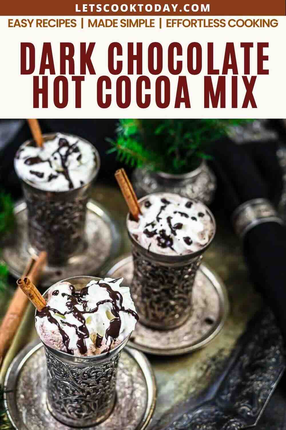 Three ornate cups filled with dark chocolate hot cocoa, topped with whipped cream, chocolate drizzle, and cinnamon sticks, placed on a decorative metal tray.