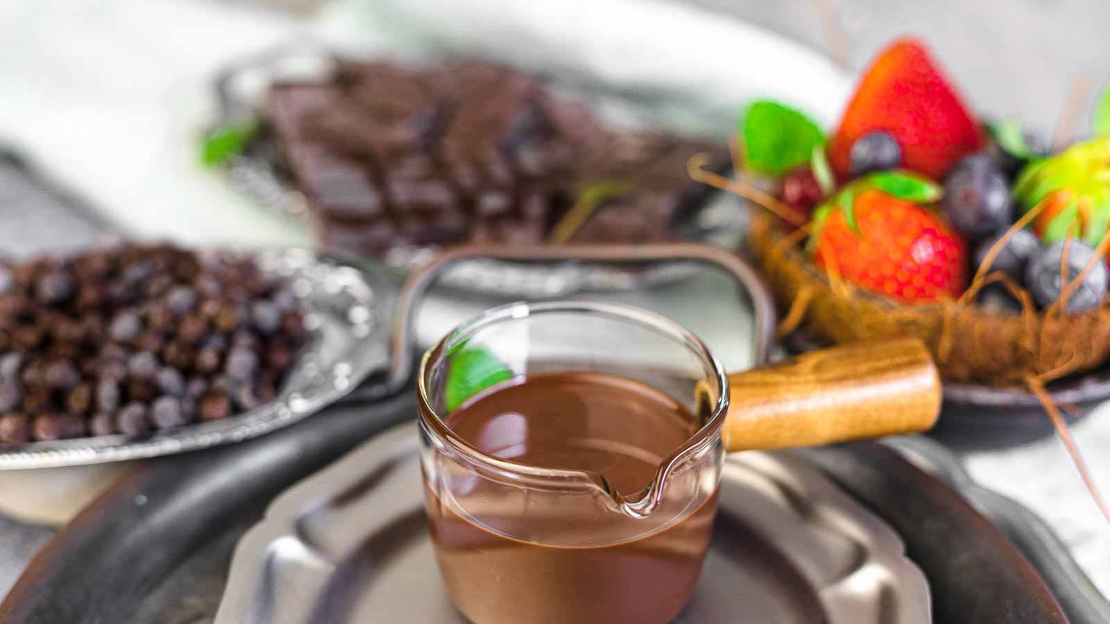 Sugar-Free Chocolate Magic Shell in a glass with berries behind.
