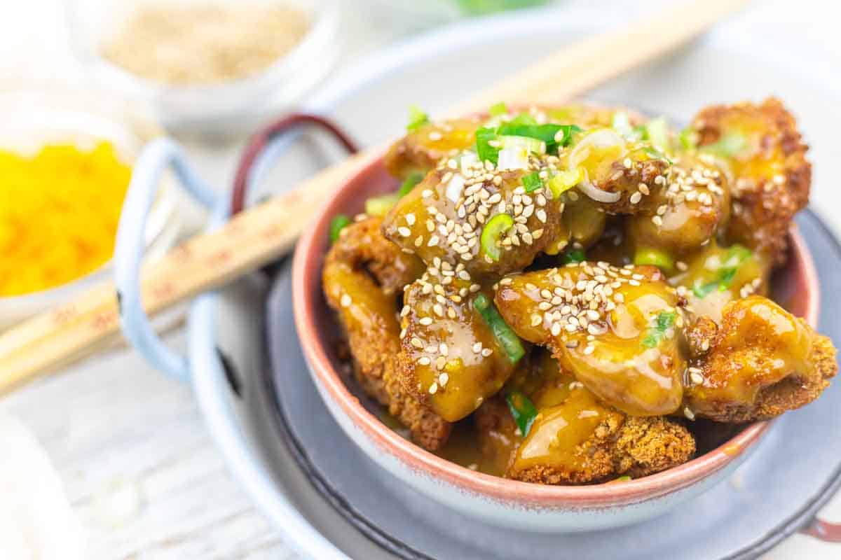 Orange chicken served in bowl with sesame garnish.
