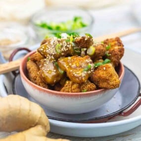 Bowl of crispy orange chicken with sesame seeds.