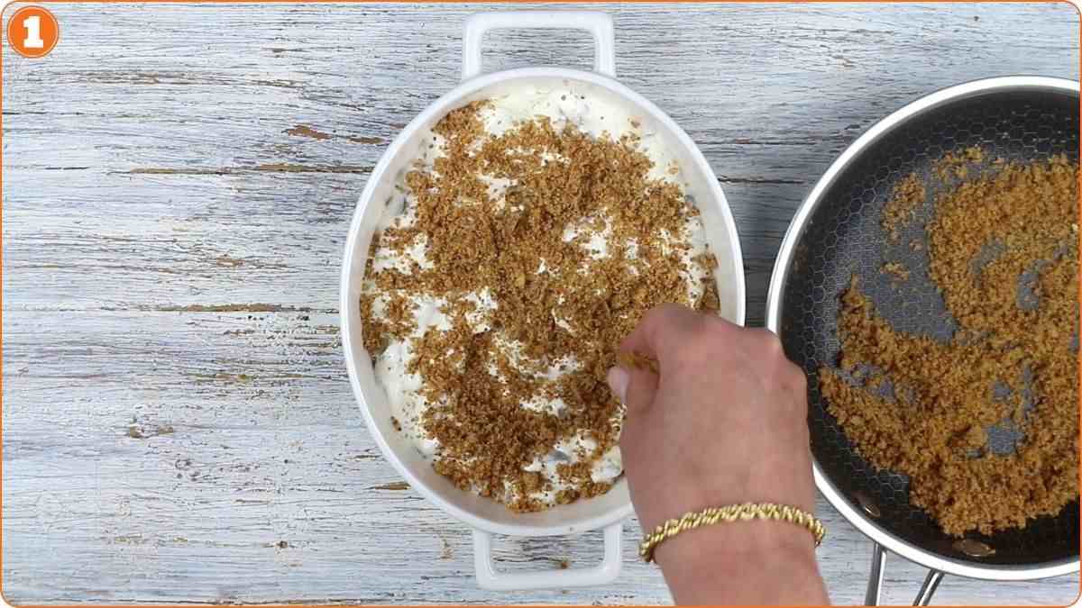 Sprinkling toasted breadcrumbs over creamy pickle mixture.