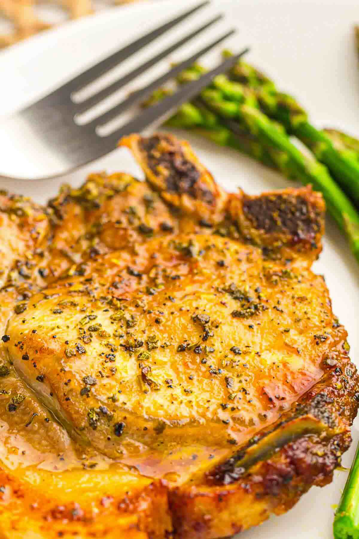 Juicy golden pork chop served with asparagus.