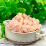 Bowl of ground chicken breast and parsley.