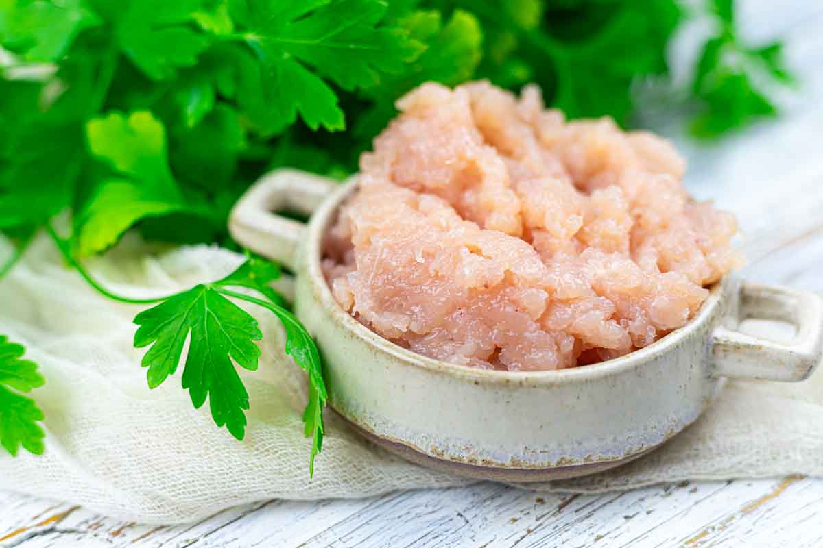Ground chicken breast with parsley on table.