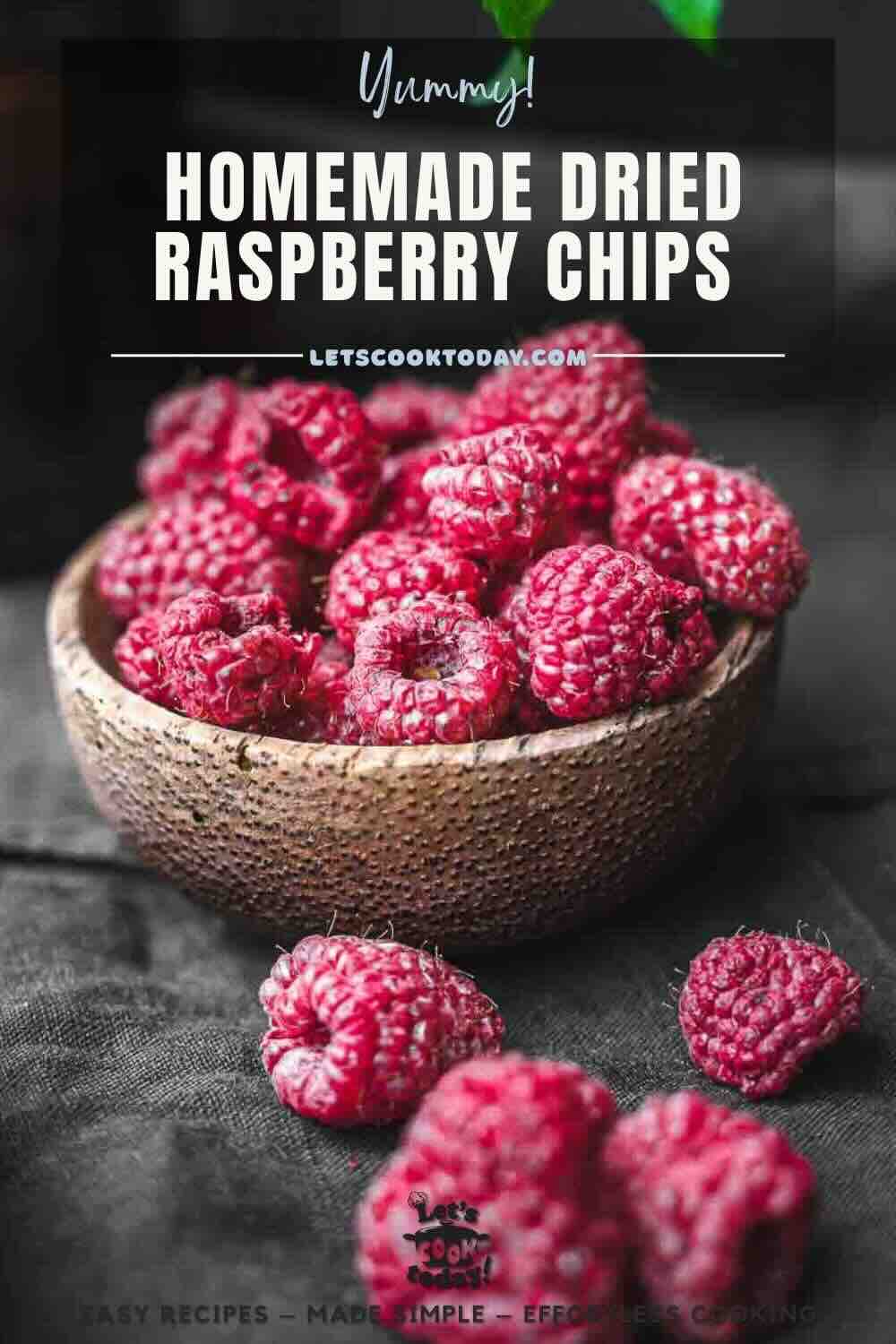 A wooden bowl filled with dried raspberry chips sits on a dark surface, with a few chips scattered nearby. Text reads: "Homemade Dried Raspberry Chips.