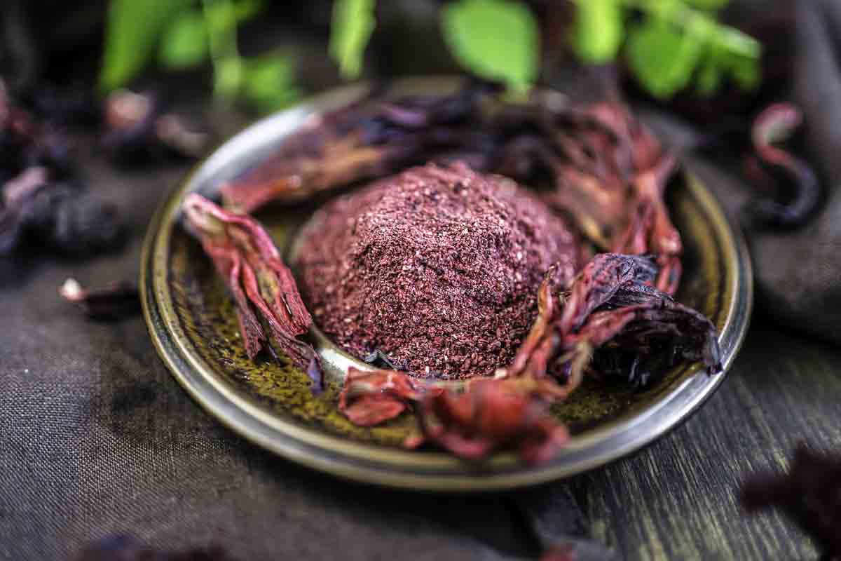 Bowl of powdered hibiscus with petals.