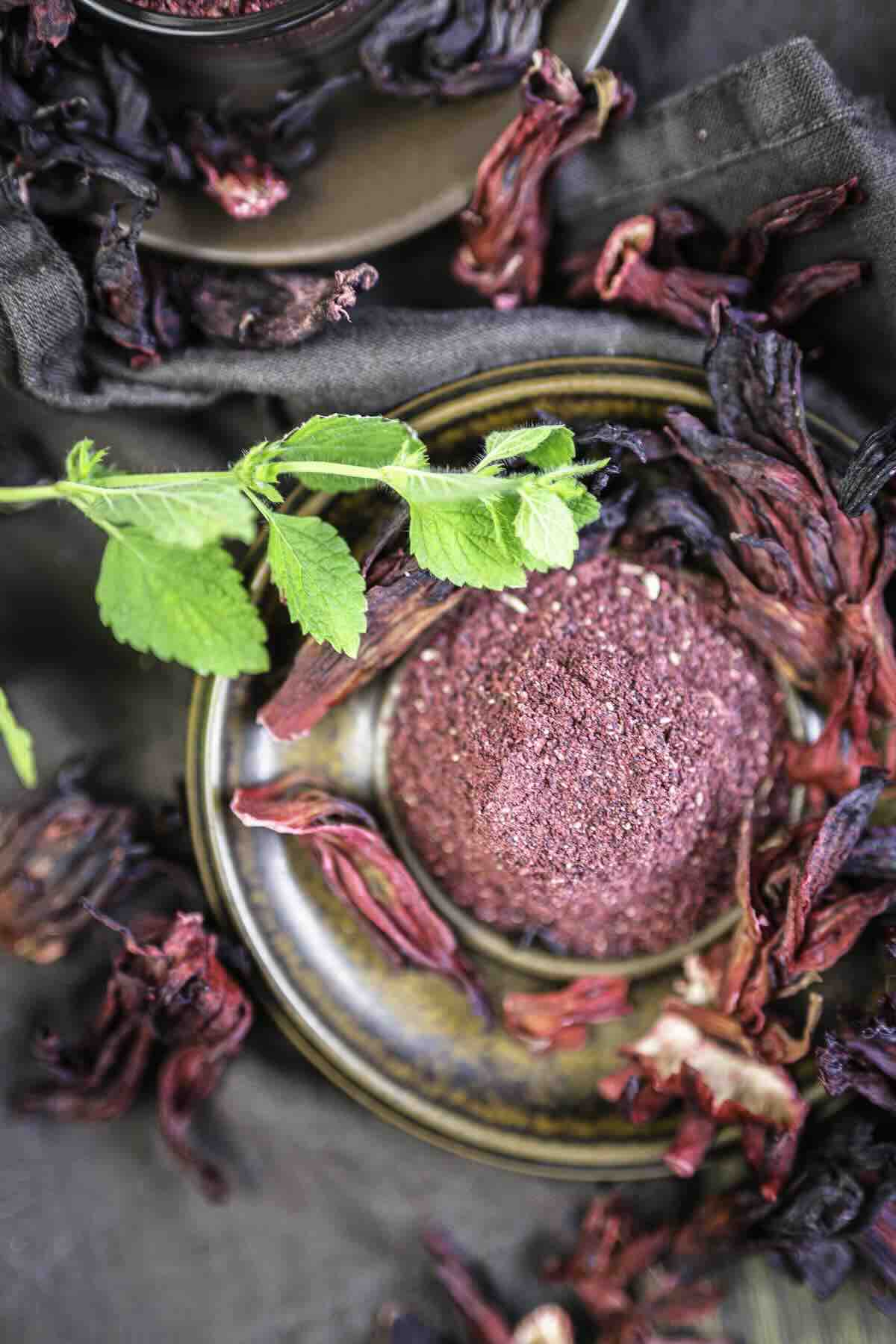Hibiscus powder on plate beside green leaves.
