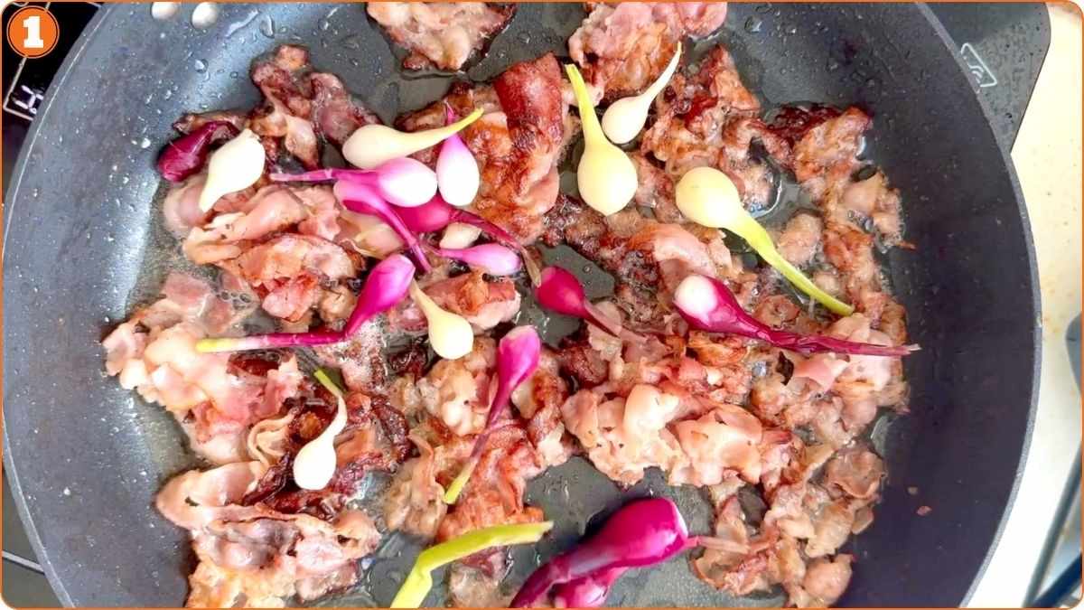 Slices of bacon and small whole onions are being cooked together in a frying pan.
