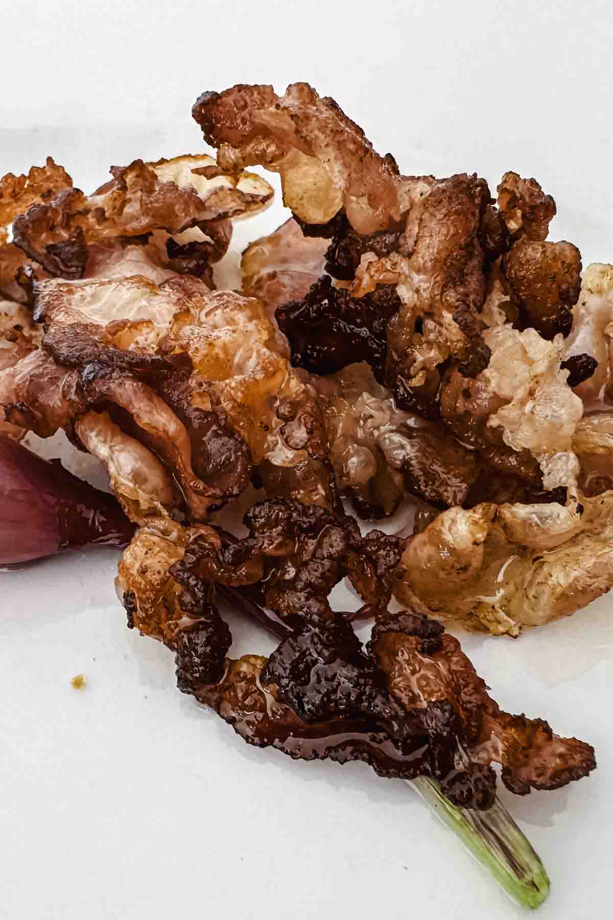 Crispy cooked bacon strips piled on a white plate.