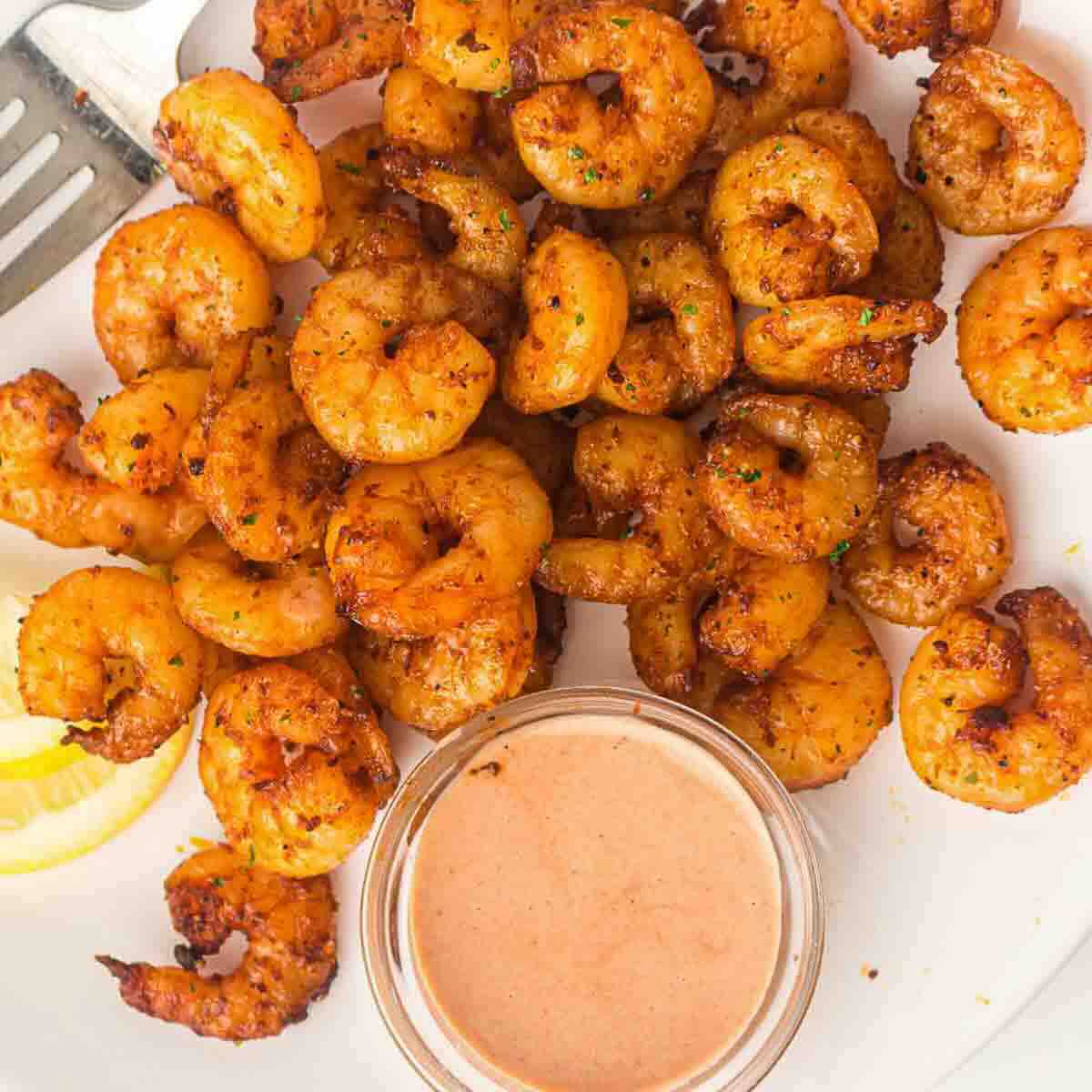 Crispy shrimp beside bowl of dipping sauce.