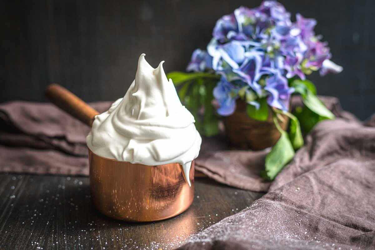 Creamy meringue icing displayed with purple flowers.