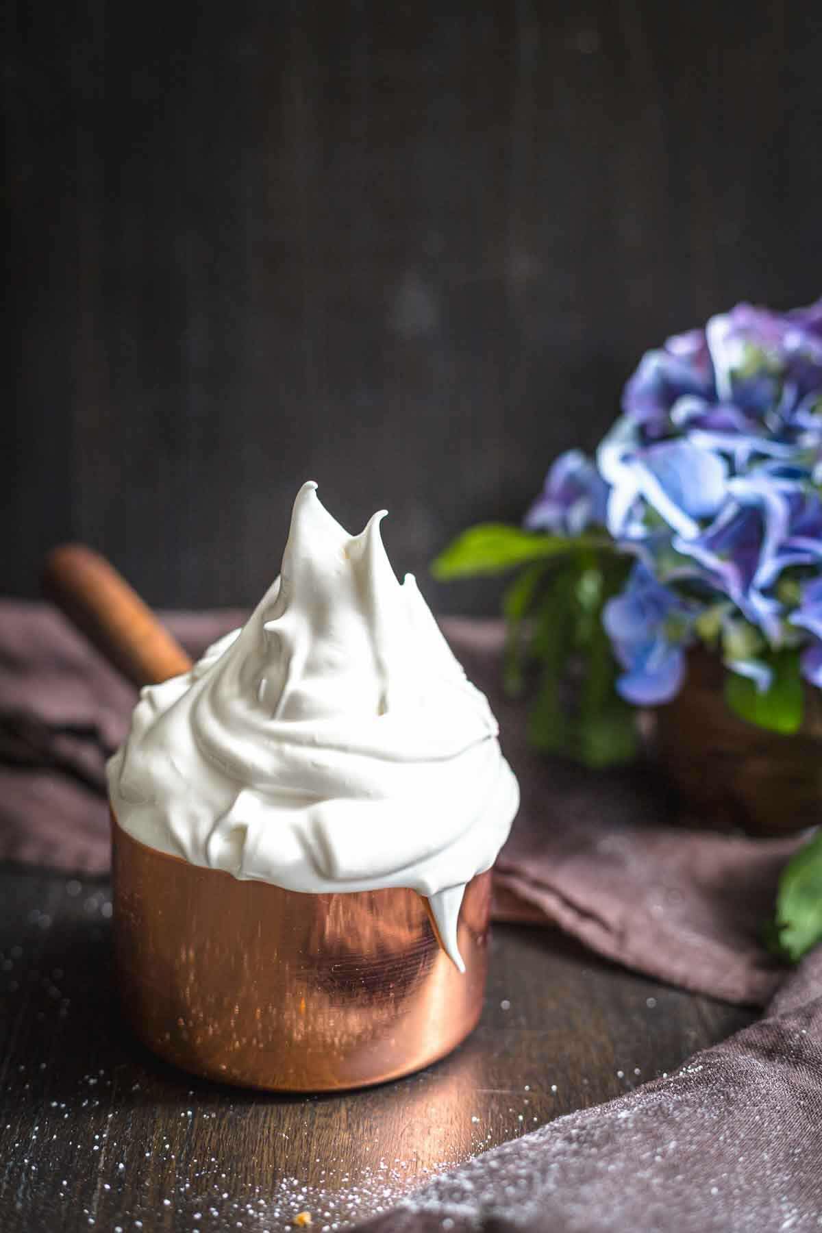 Copper pot filled with glossy meringue icing.