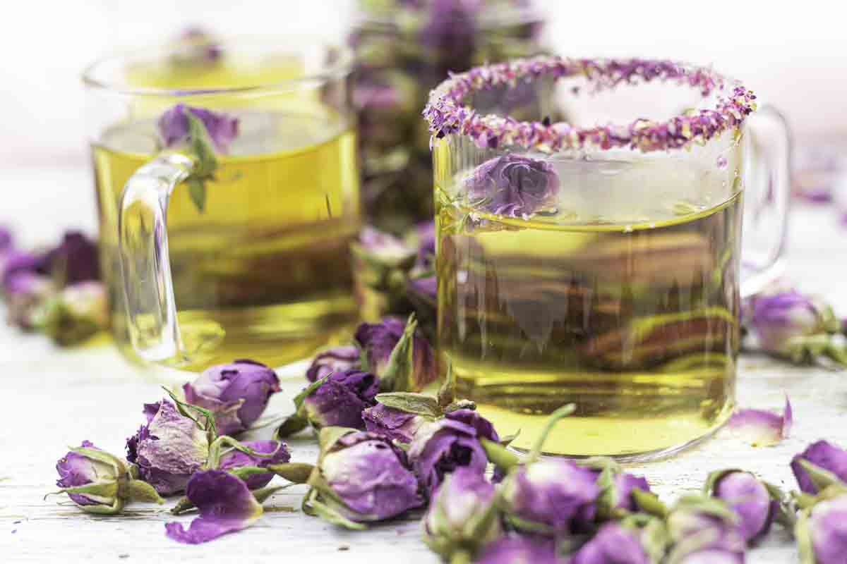 Two rosebud tea cups with flower garnish.