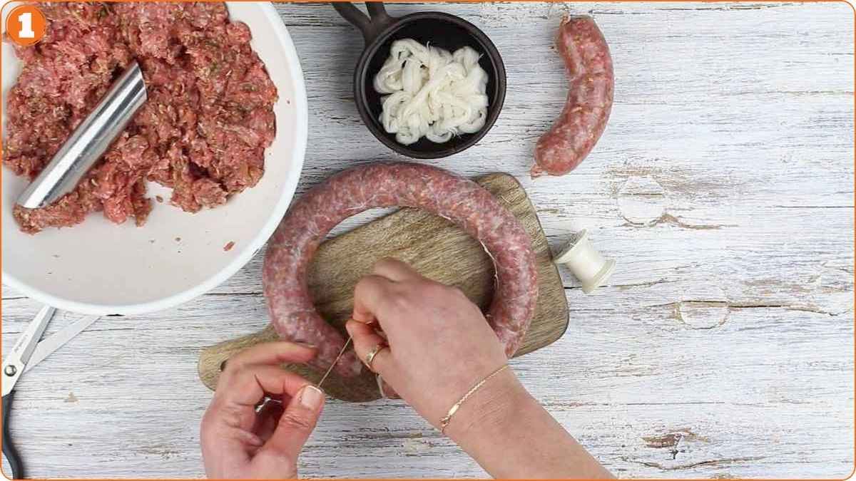 Tying homemade sausage link on cutting board.