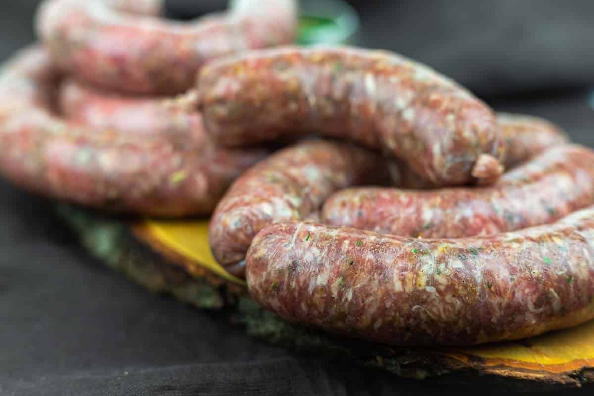 Sausages stacked on rustic wooden serving board.
