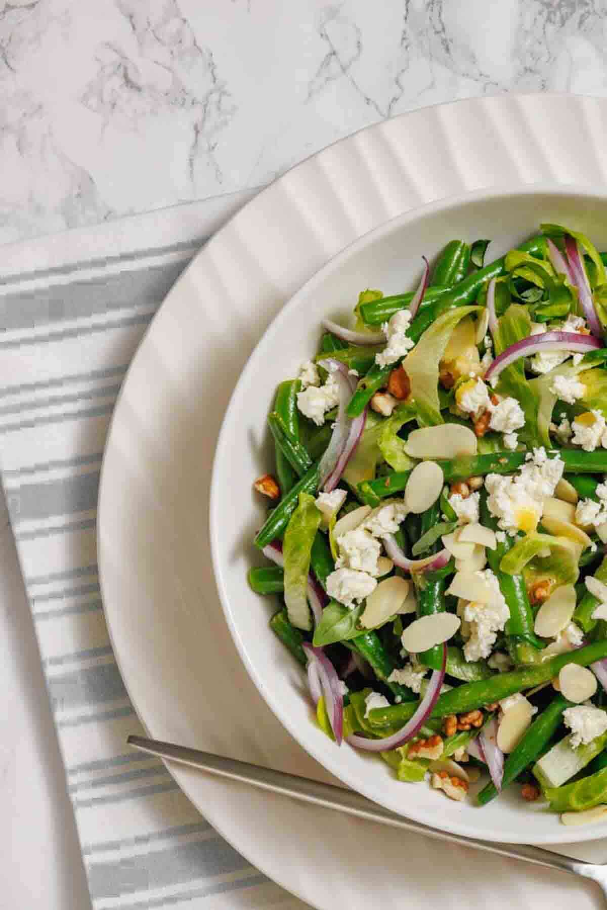 Green bean salad on marble table setting.