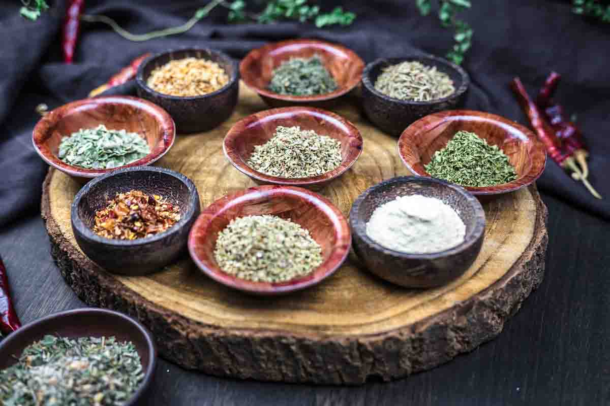 Various Italian spices arranged on wooden board.