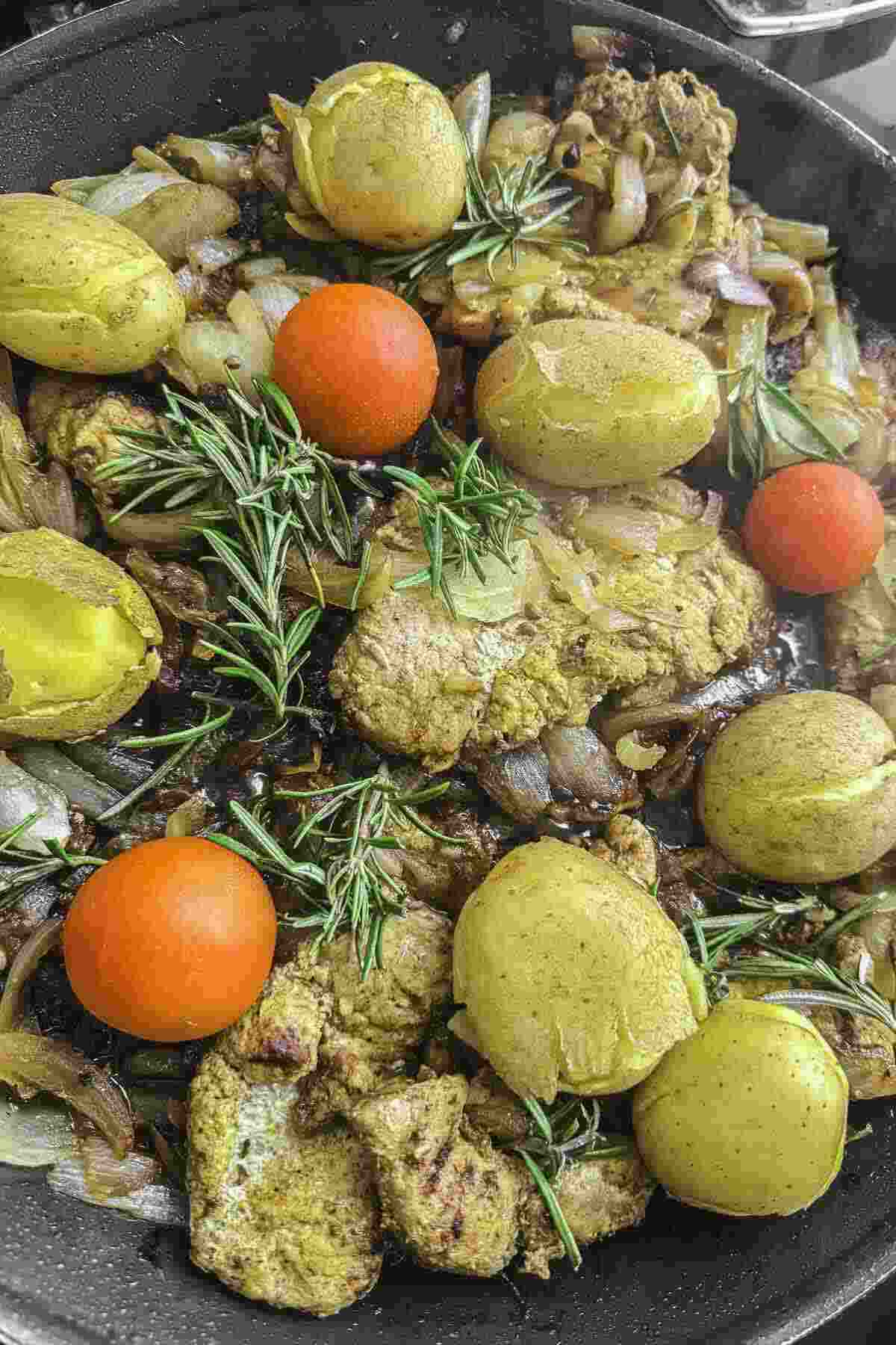 Pork cutlets in skillet with onion and herbs.