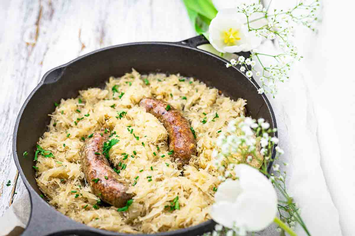 Cast iron skillet filled with sausage sauerkraut.
