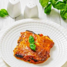 Cheesy baked eggplant parmesan with basil garnish.
