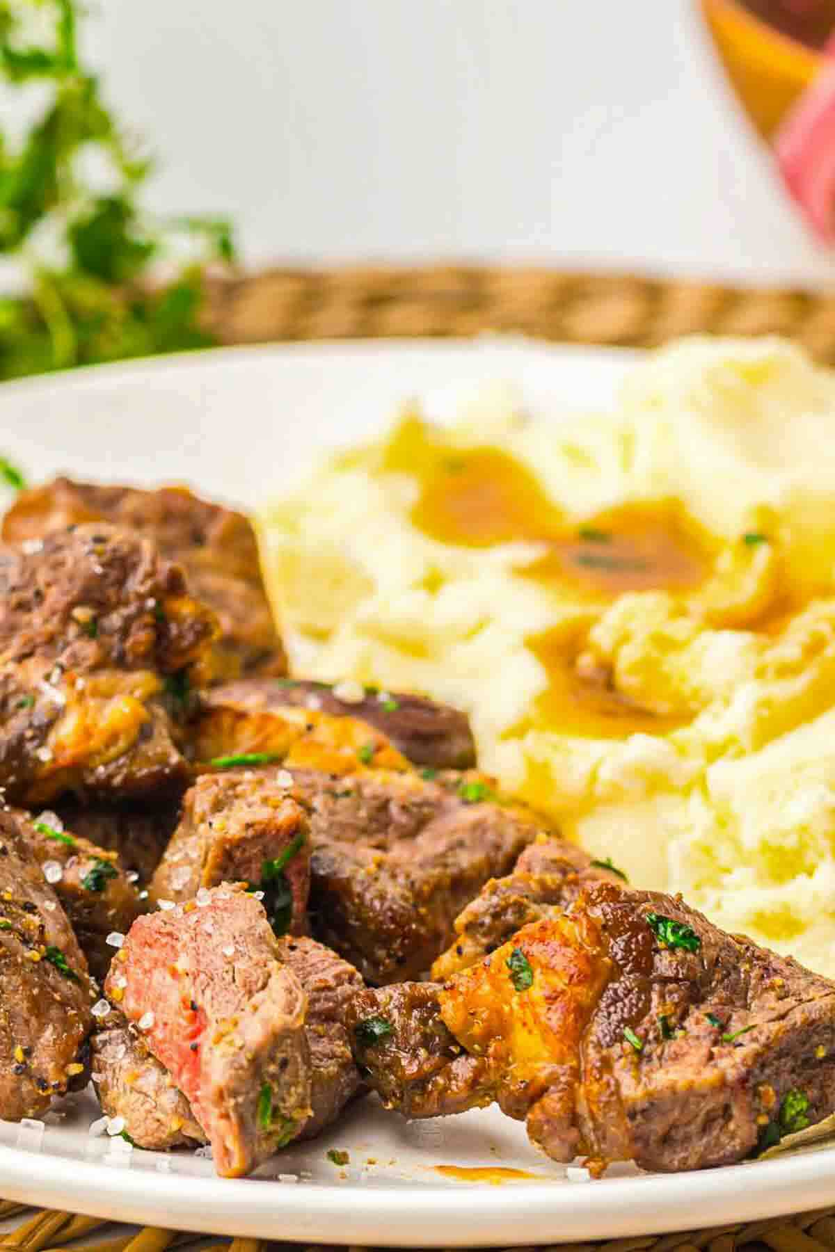 Juicy ribeye steak cubes on white plate.