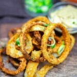 Stack of golden onion rings on board.