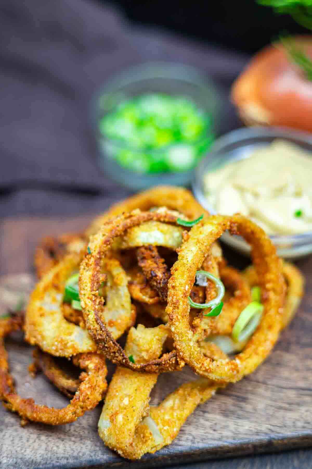 Air-fried onion rings in a wooden board.