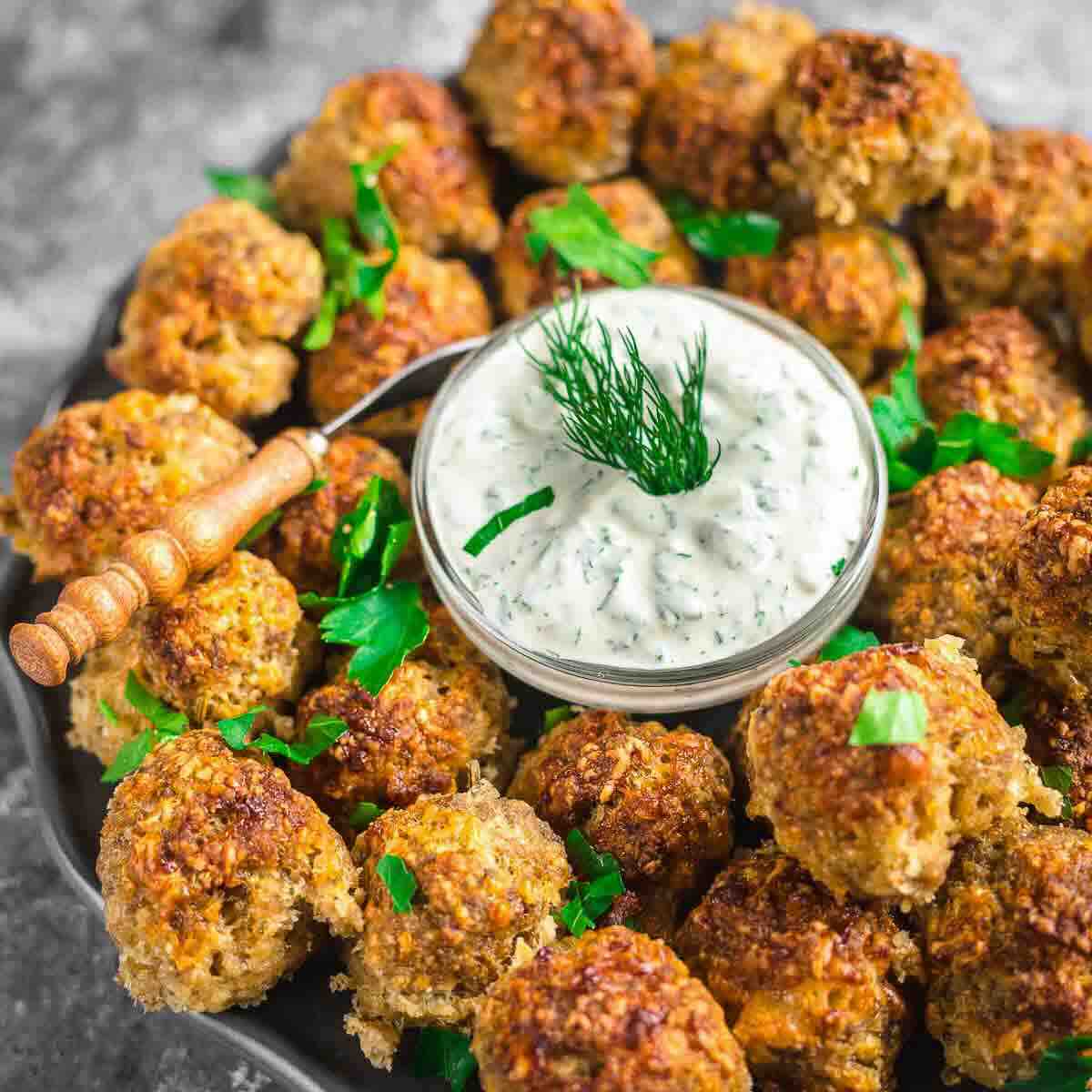 Golden sausage balls near creamy herb dip.