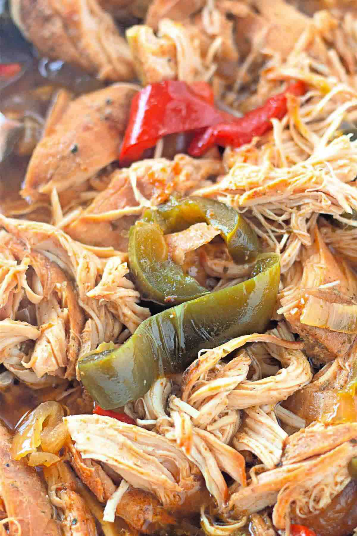 Shredded cooked chicken with pieces of green and red bell peppers in a savory sauce.