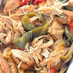 Shredded cooked chicken mixed with sliced green and red bell peppers in a savory sauce.