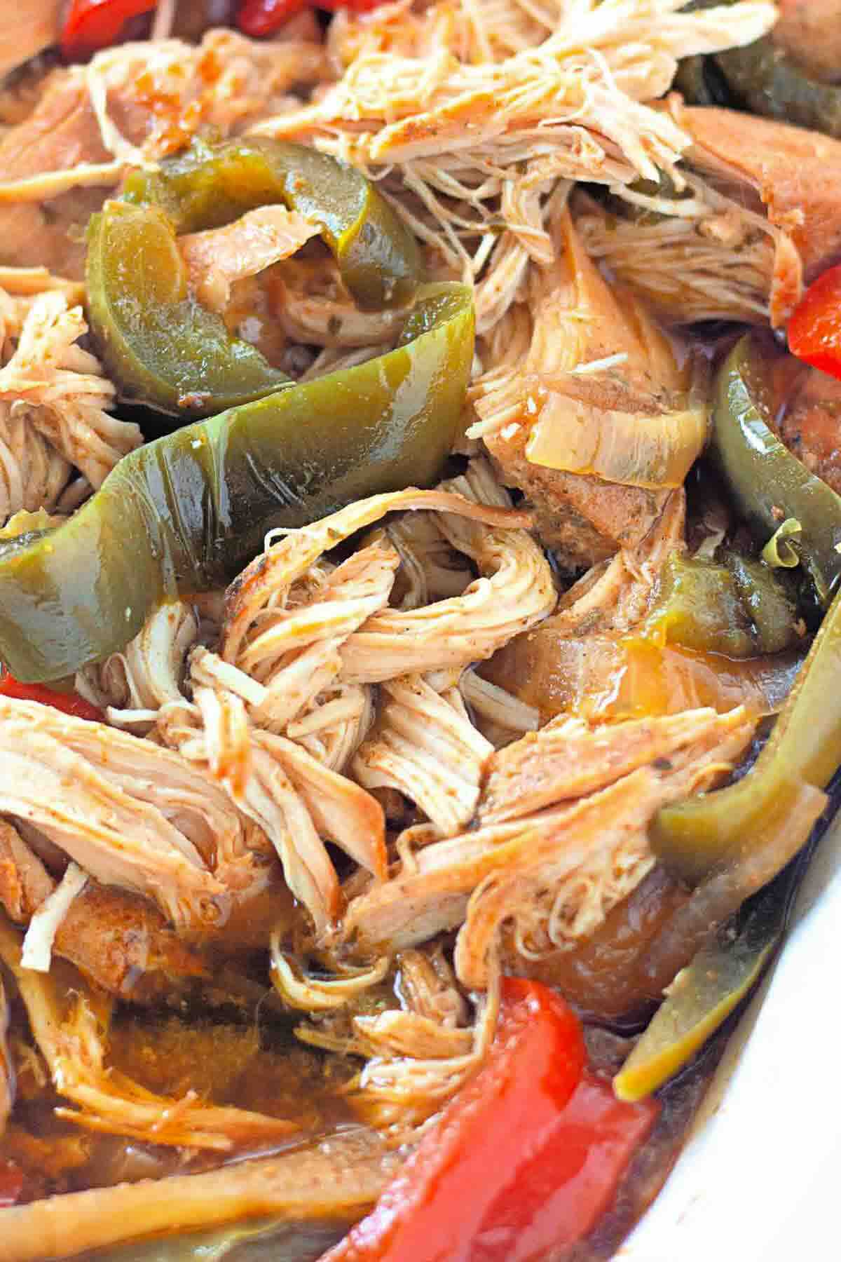 Close-up of shredded chicken cooked with green and red bell peppers in a savory sauce.