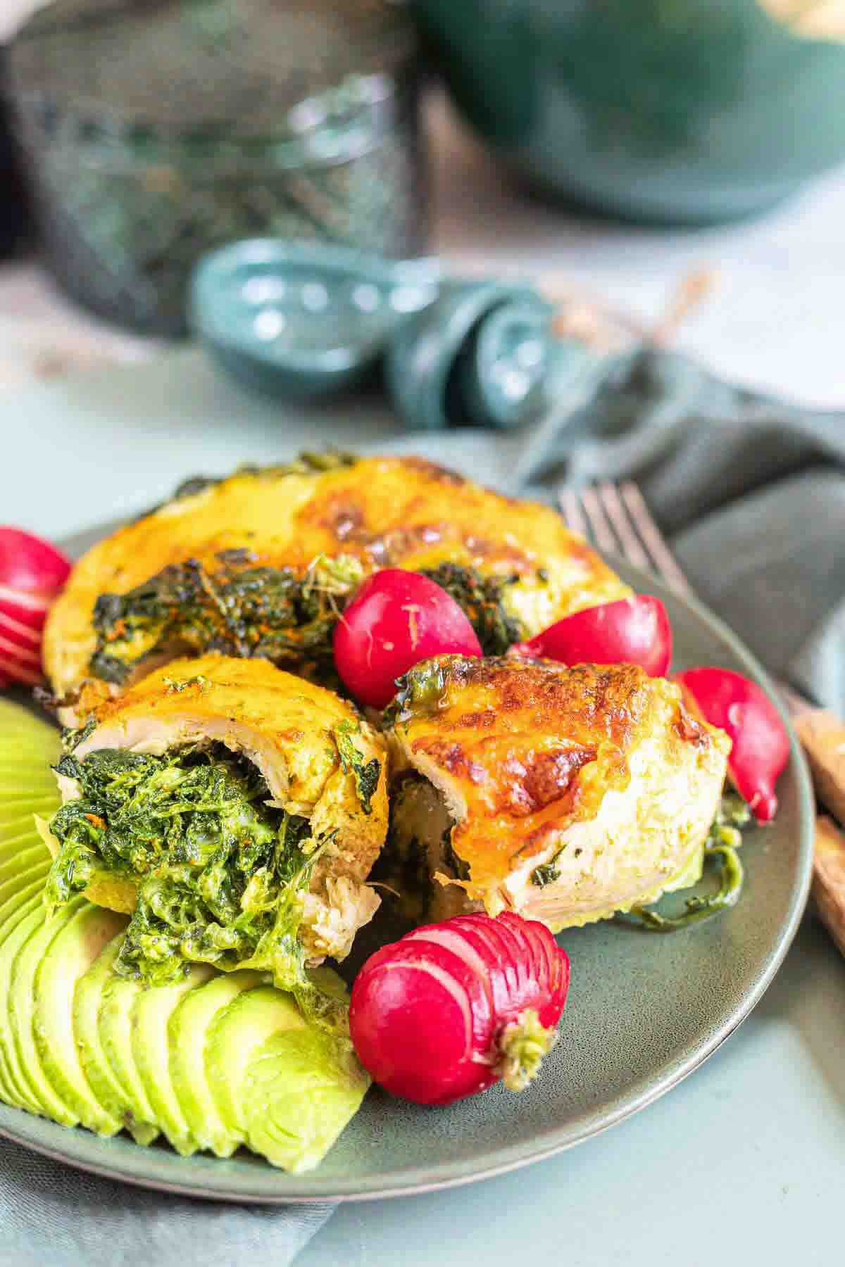 Plated stuffed chicken rolls with radishes and avocado.