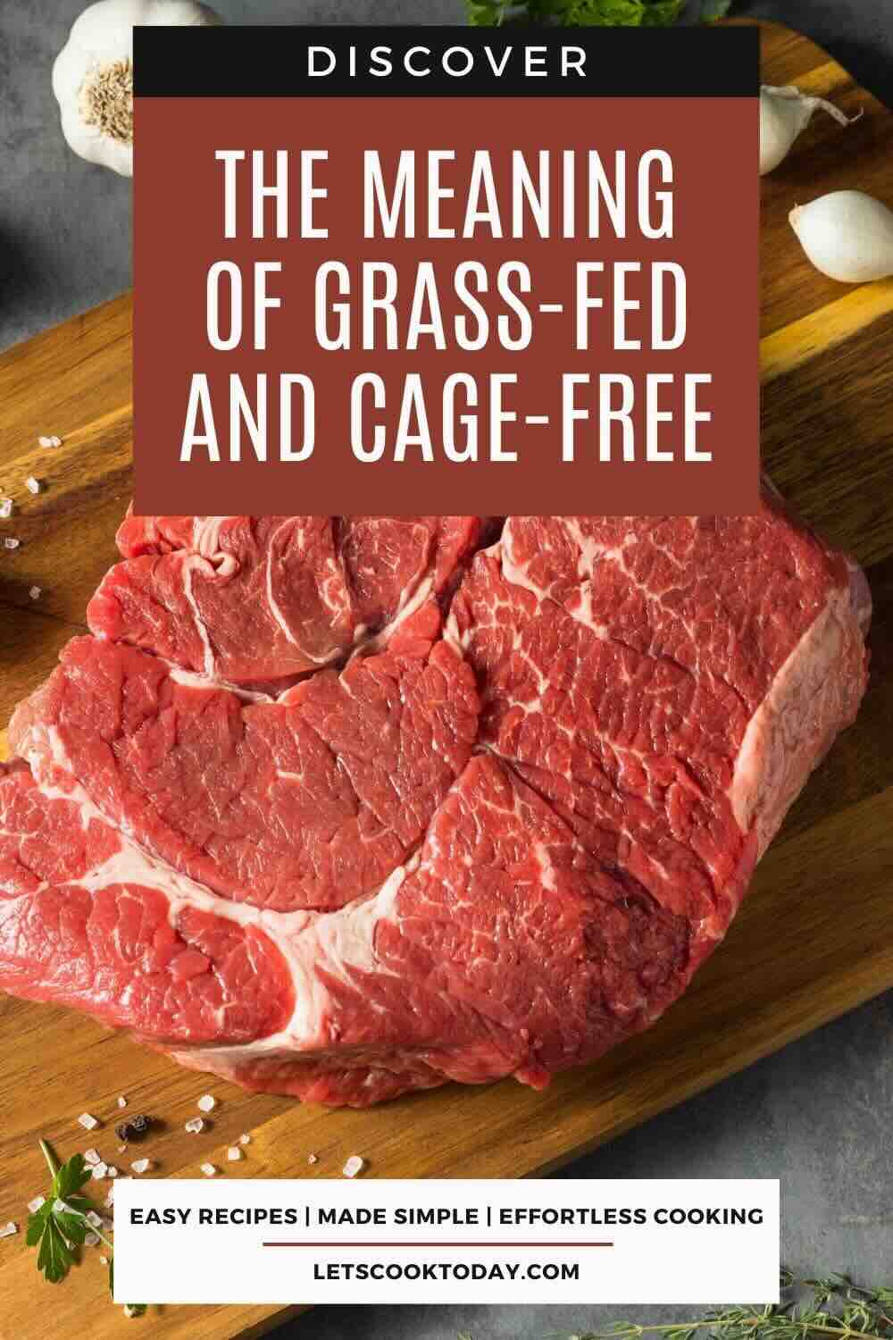 Raw beef steak on a wooden cutting board with salt and garlic, overlaid with text about the meaning of grass-fed and cage-free meat.