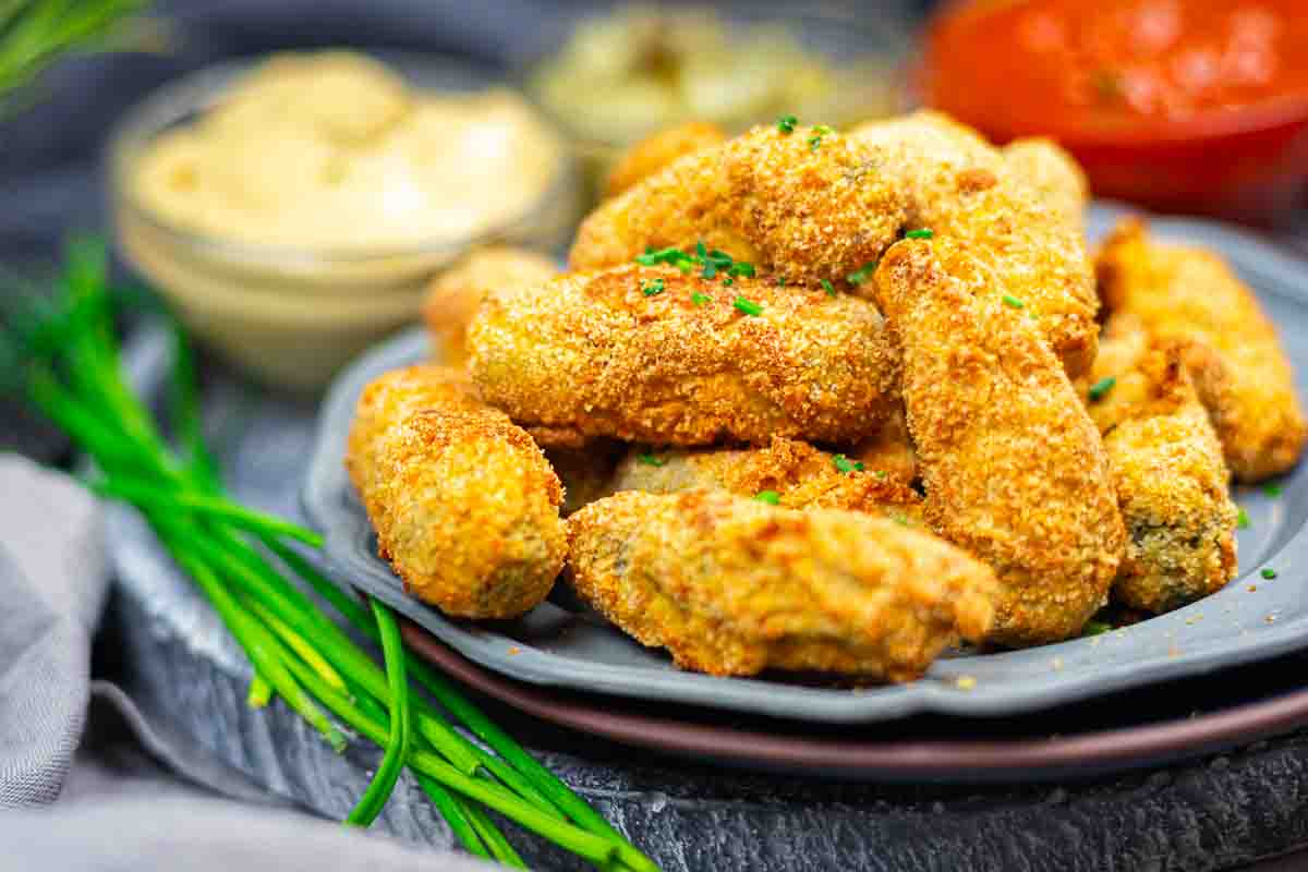 Breaded dill gherkins served on grey plate.
