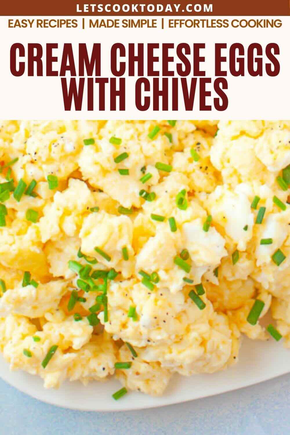 Scrambled eggs mixed with cream cheese, topped with chopped chives, served on a white plate.