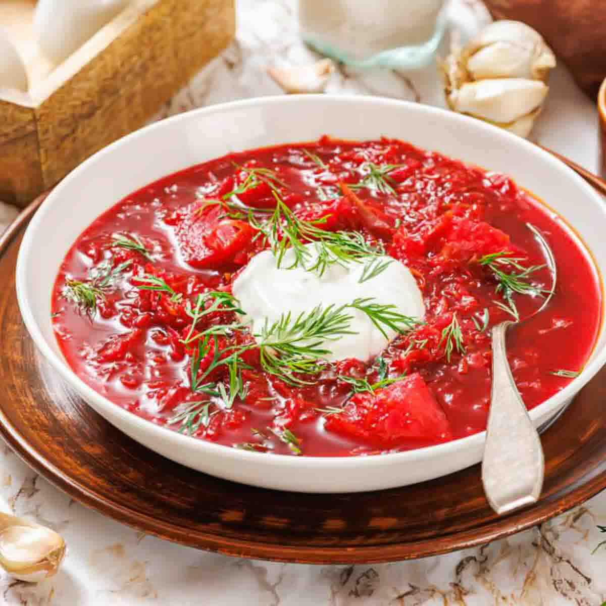 A bowl of red borscht topped with a dollop of sour cream and fresh dill.